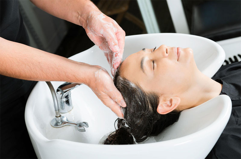 Hair being gently shampooed at a salon wash basin.